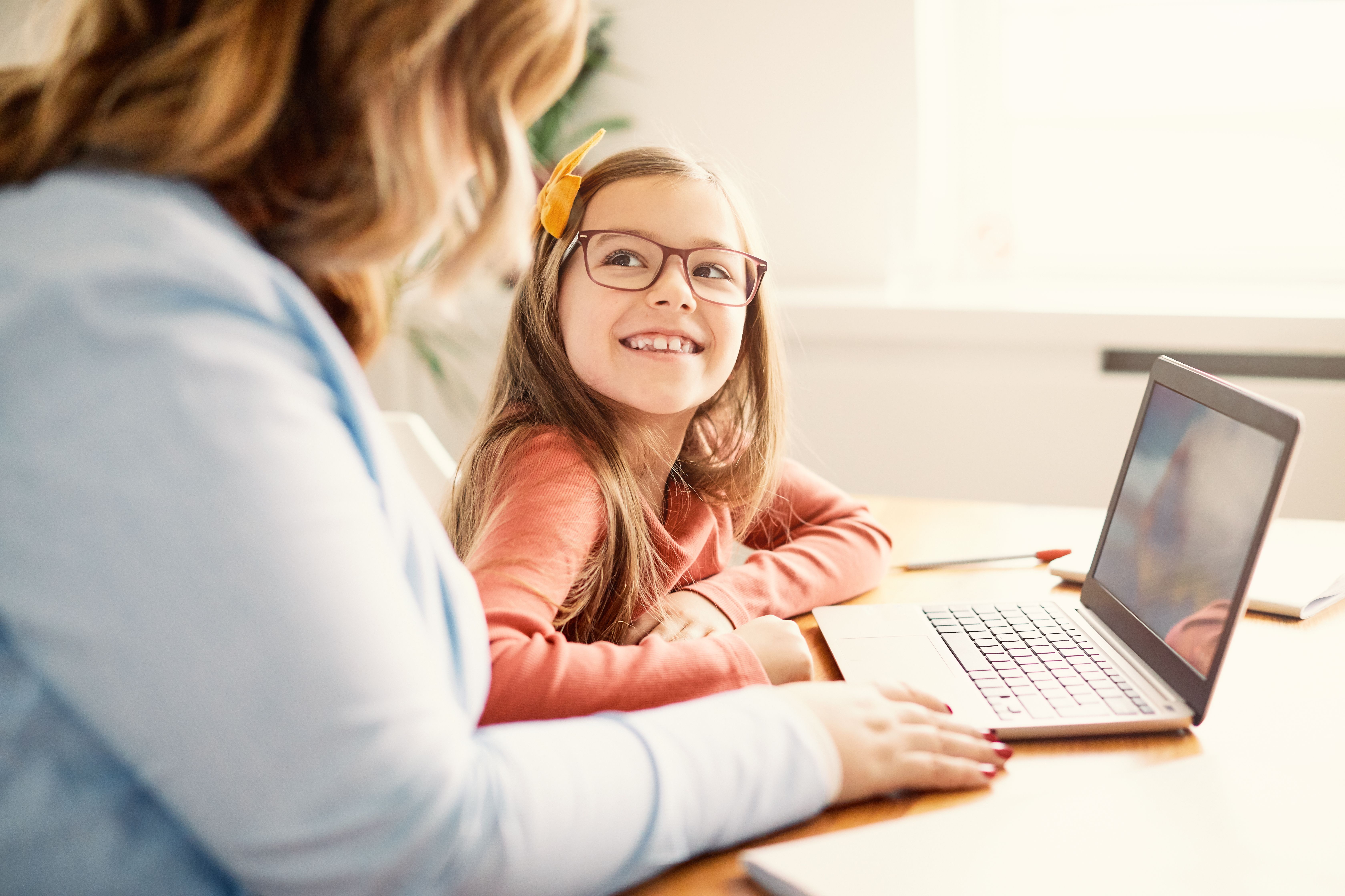 Chuffed  kid looking parent using laptop